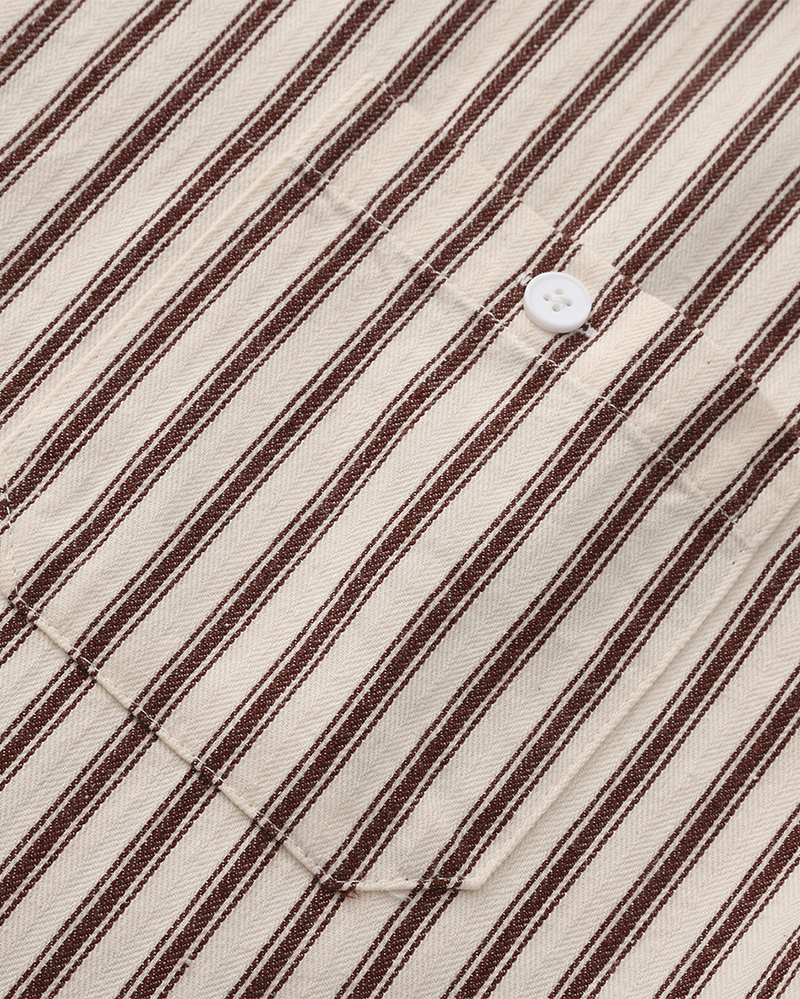 Detail of striped shirt chest pocket and button in brown and cream