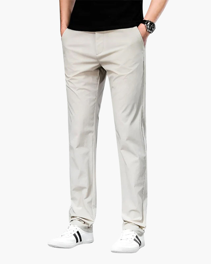 Man in stone-beige straight chino trousers with a black tee and white trainers, hands in pockets