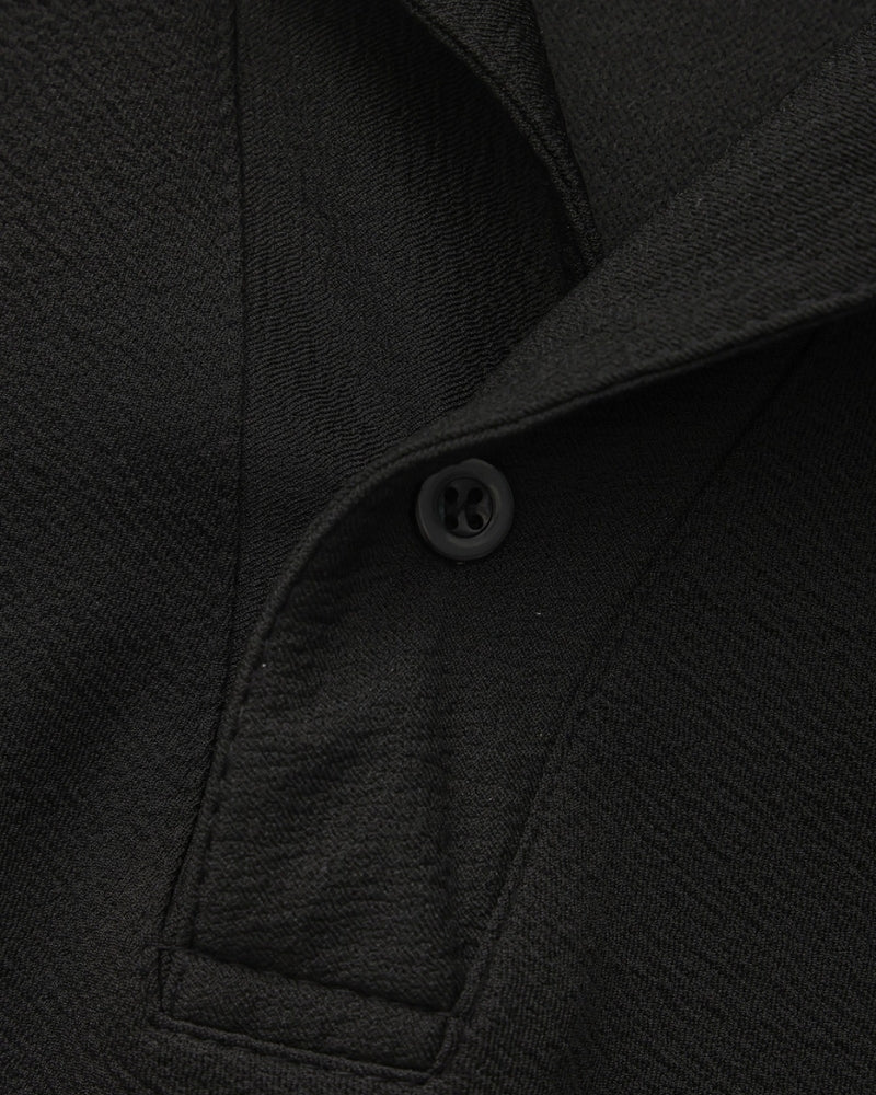 Close-up of a black polo button placket and crinkle-textured fabric