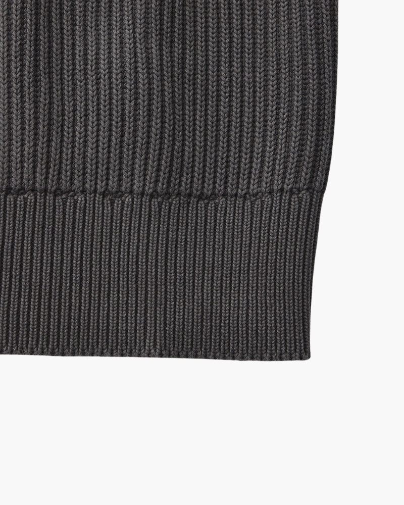 Close-up of charcoal-grey rib-knit jumper hem with wide ribbed waistband, flat-lay on white