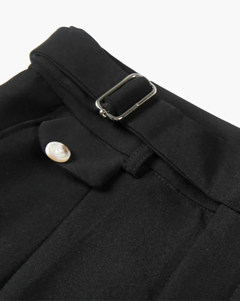 Primer plano de la cinturilla de unos shorts negros con correa de hebilla plateada y pestaña con botón efecto perla