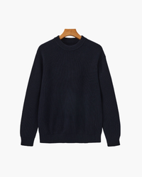 Jersey de cuello redondo de canalé grueso azul marino con puños y bajo de canalé, vista frontal en una percha de madera