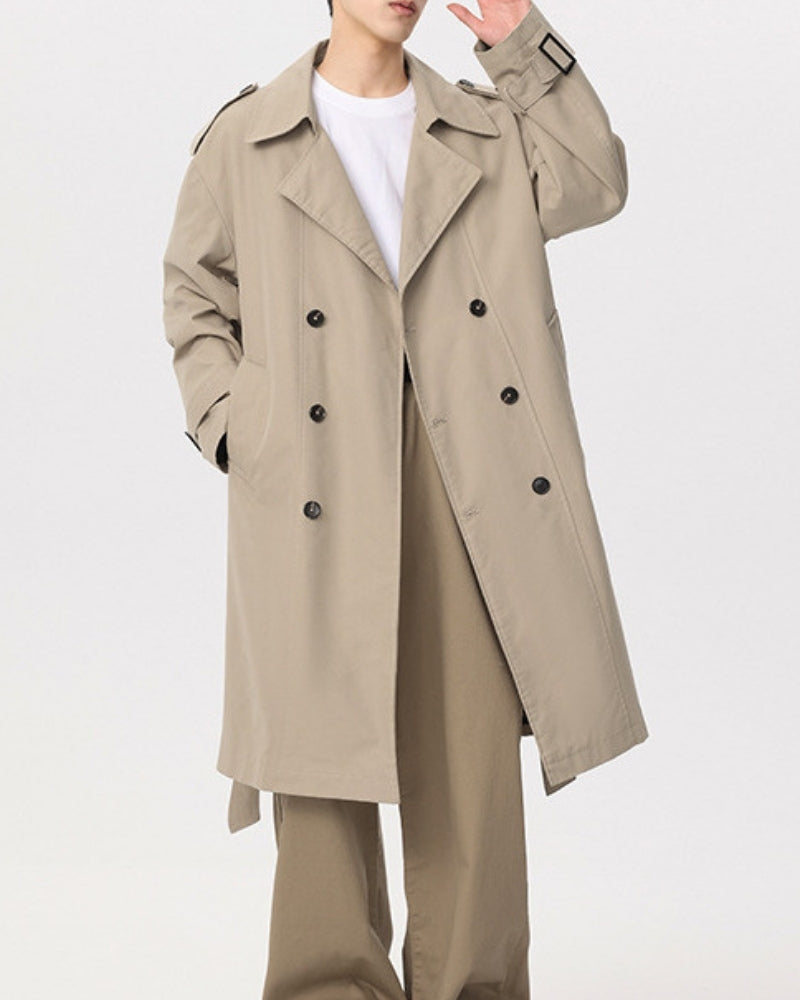 Man in a beige double-breasted trench coat with raised hand and buckled cuff strap