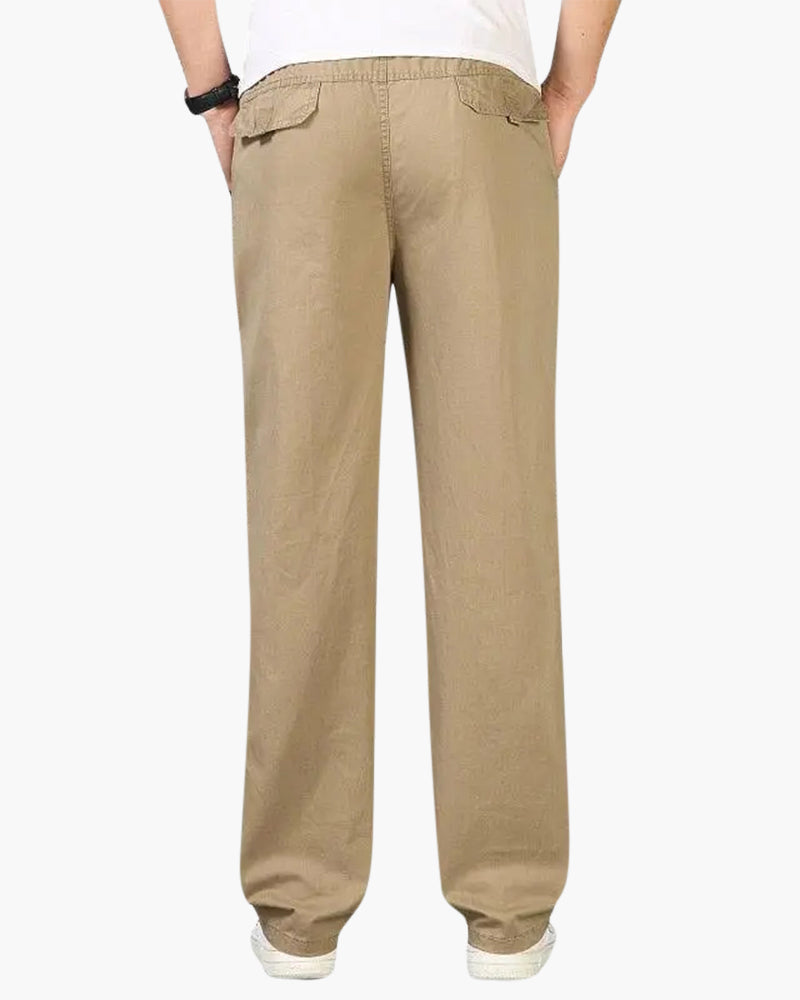 Back view of khaki cotton-linen trousers showing flap back pockets and elastic waist, on model