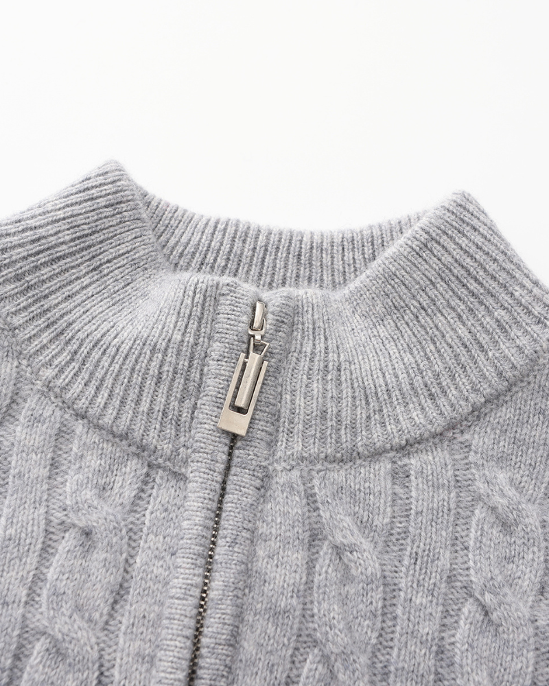 Close-up of a light grey cashmere half-zip collar and silver zip pull with cable knit below