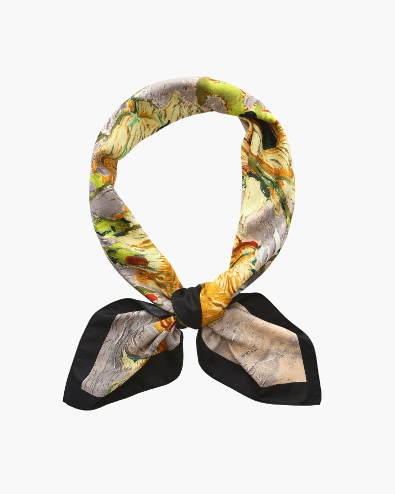 Yellow floral painterly scarf with black border knotted in a loop, flat-lay