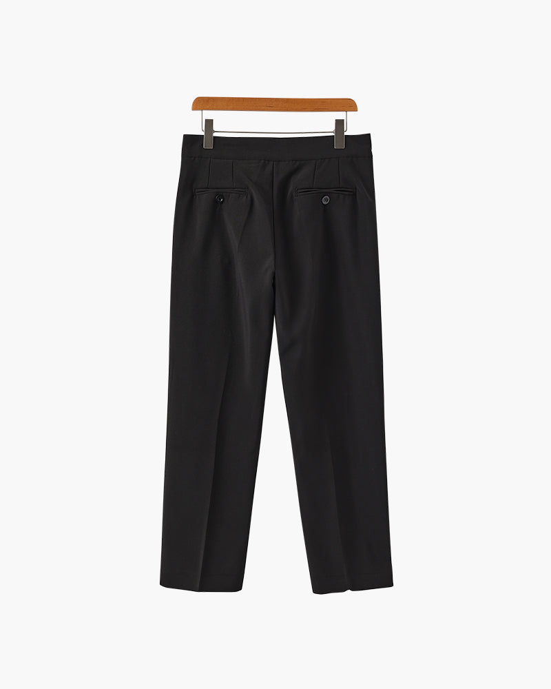 Back view of black pleated trousers with two button-through jetted pockets, on a wooden hanger