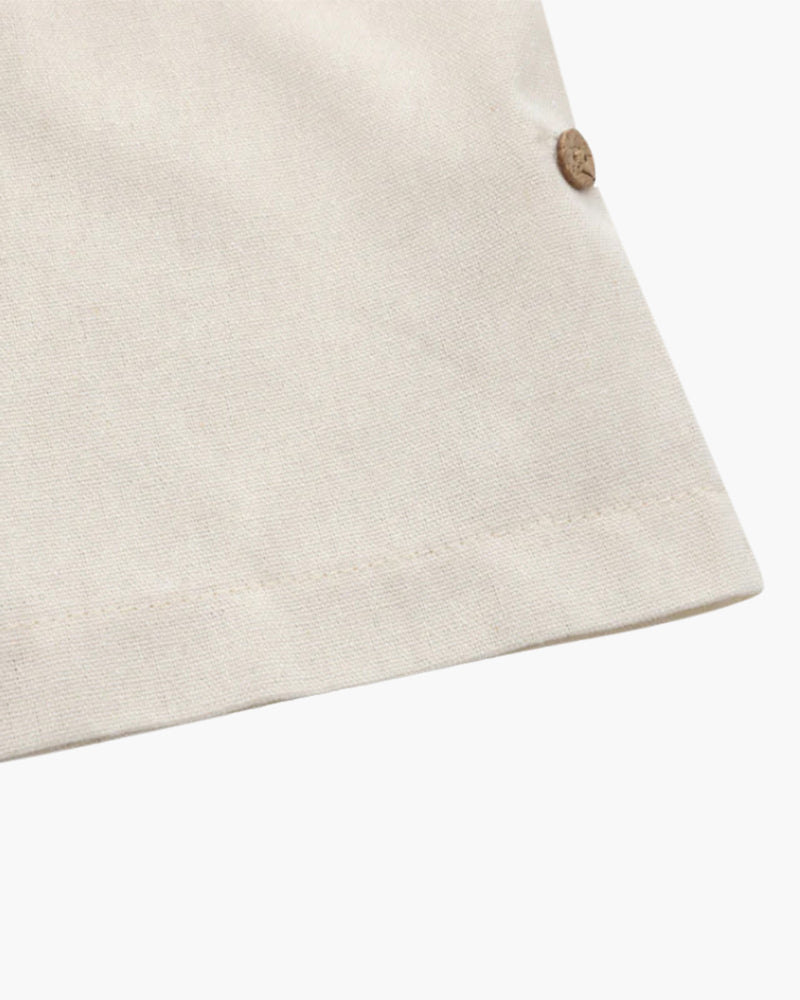 Close-up of a cream linen polo sleeve hem with button tab, flat on white