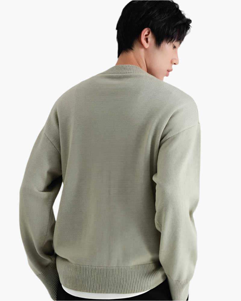Rückansicht eines salbeigrünen Woll-Pullovers mit Stehkragen und schwarzer Hose, am Model