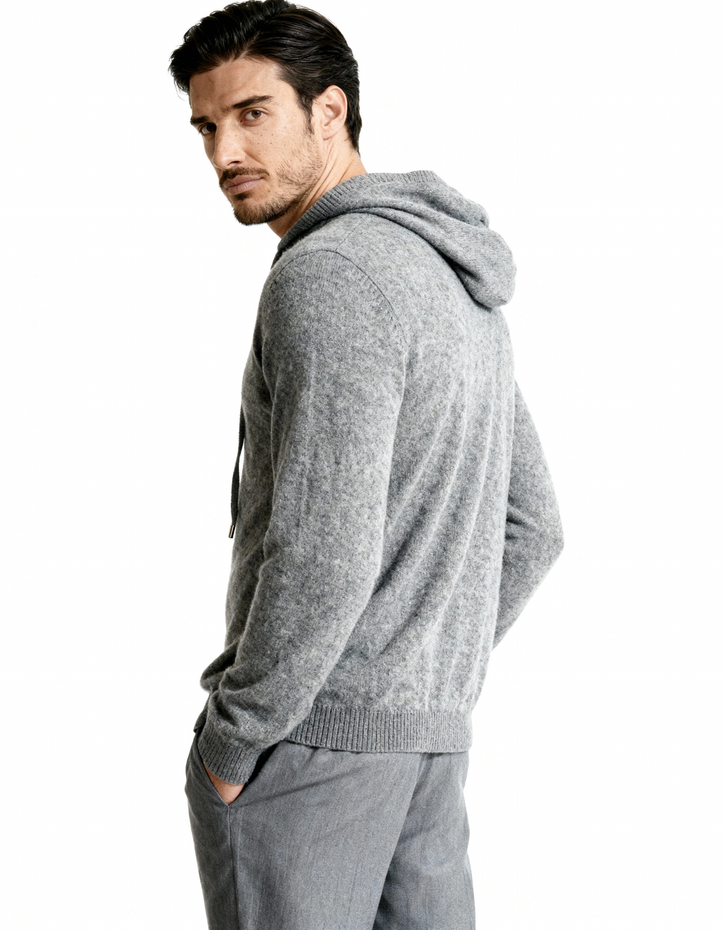 Side view of a grey cashmere hoodie showing the hood and relaxed sleeve, on model