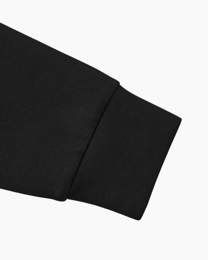 Gros plan sur le poignet côtelé d'un sweat noir, à plat sur fond blanc