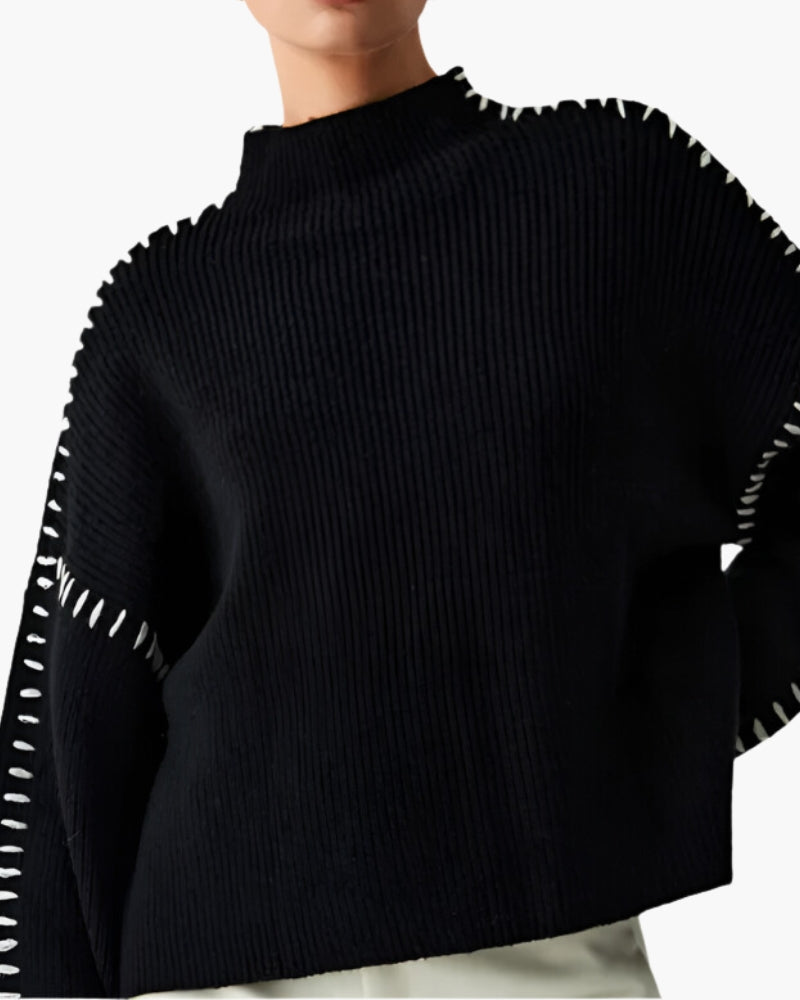 Close-up of black ribbed funnel-neck jumper with white stitching along the seams