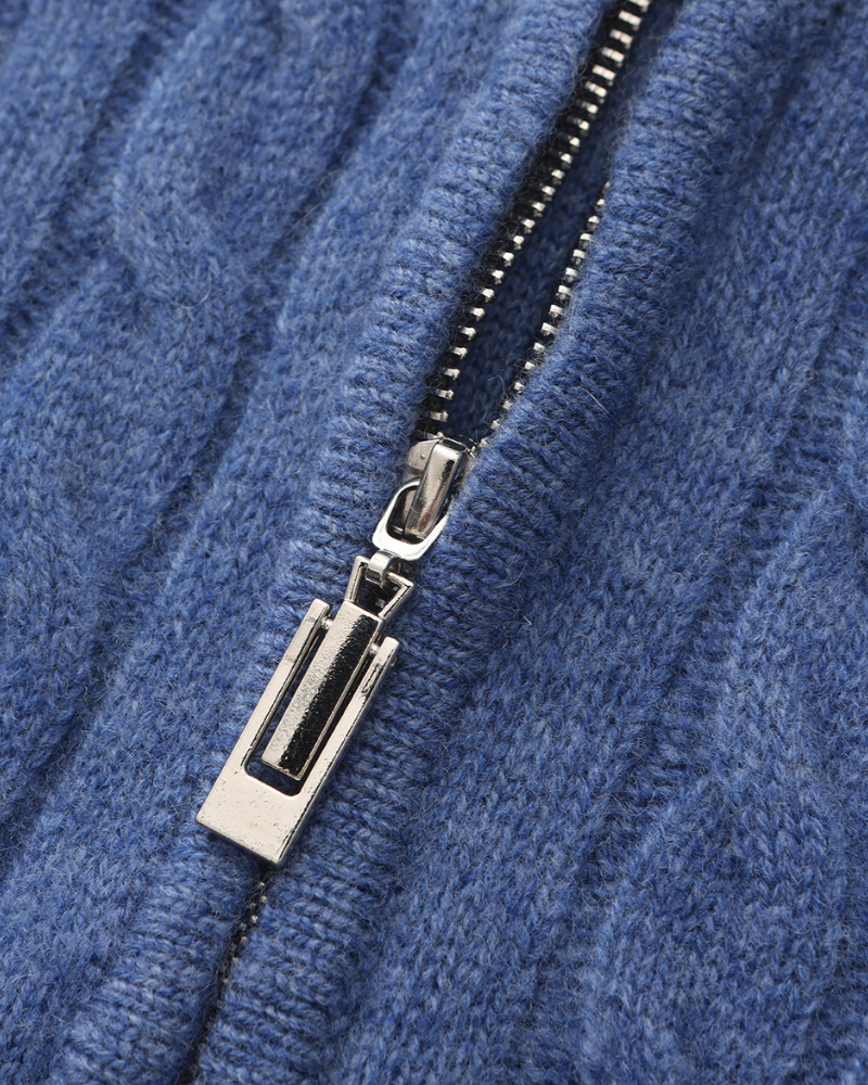 Close-up of blue cable-knit jumper with silver-tone zip puller