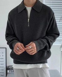 Man wearing charcoal ribbed half-zip jumper with collar over a white tee, hands clasped