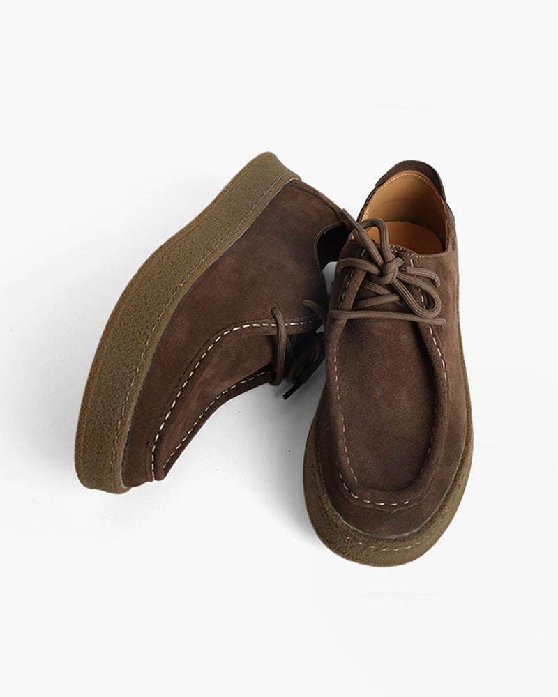 Pair of dark brown suede moc-toe lace-up shoes with gum crepe soles, one lying on its side, top-down view