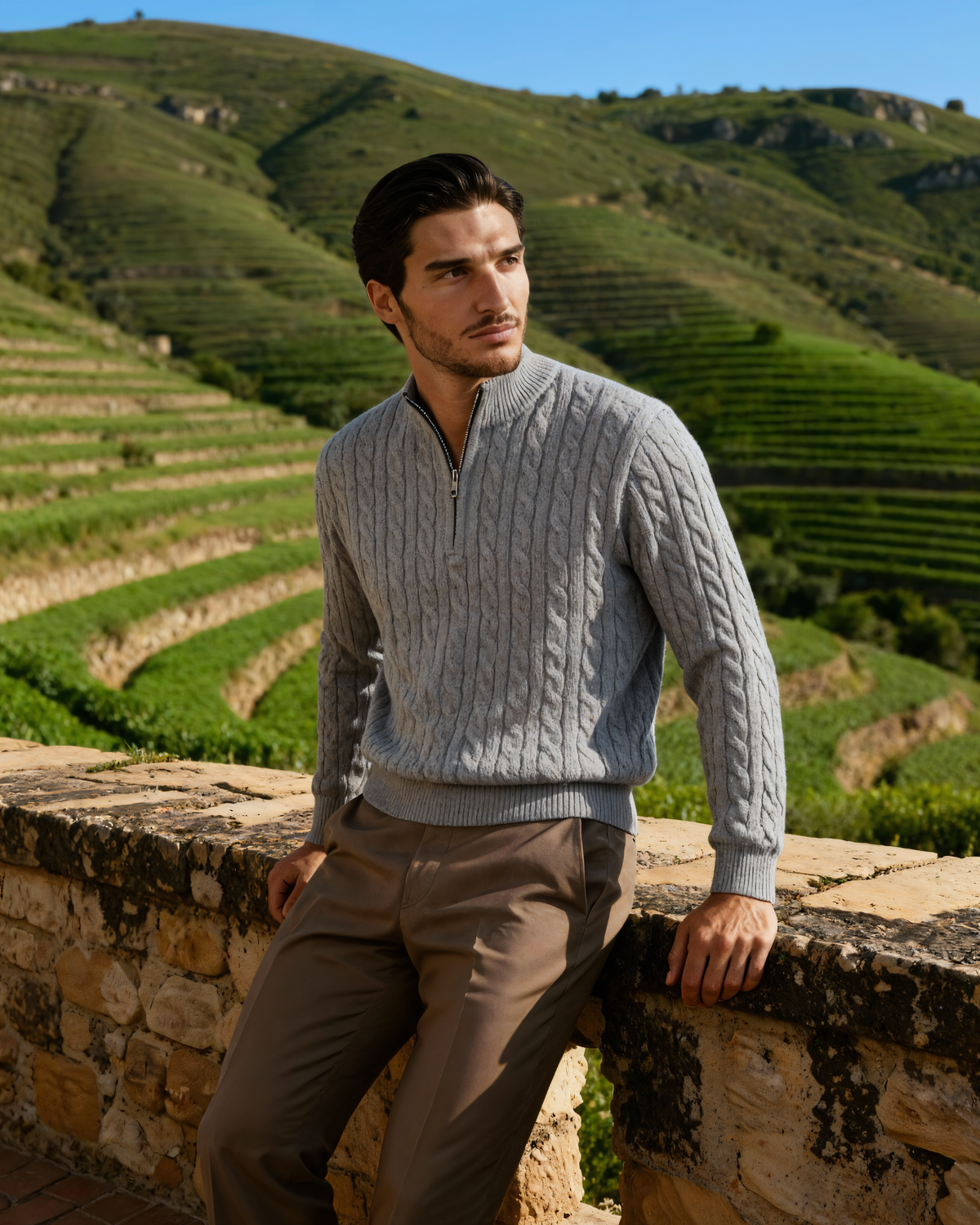 Man in a grey cable-knit cashmere half-zip jumper on a terraced hillside
