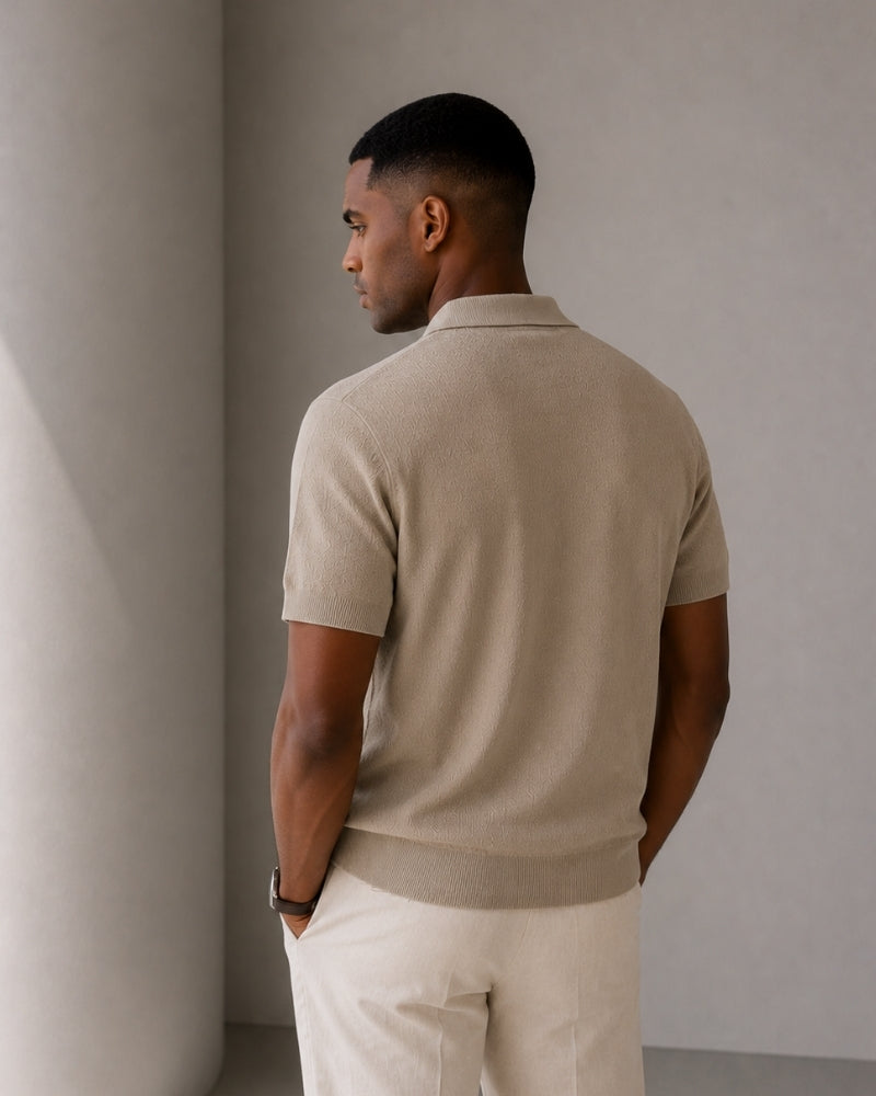 Back view of man in taupe knit polo and cream trousers, hands in pockets