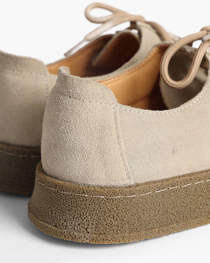 Close-up of sand-beige suede shoe heel and crepe sole with contrast stitching
