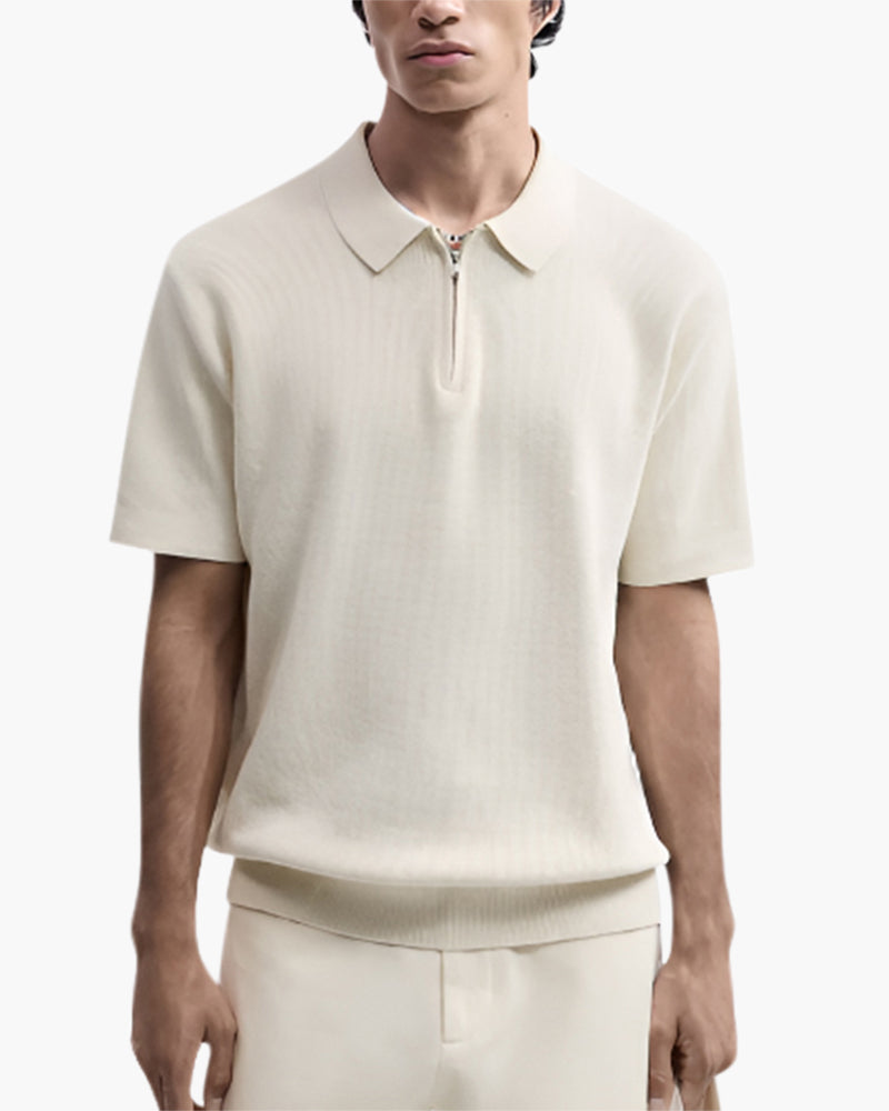 Close-up of man wearing cream knit zip polo with short sleeves and cream trousers