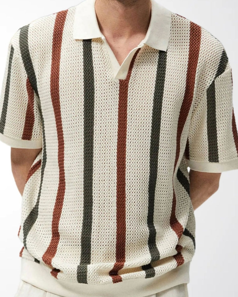 Man in cream open-knit striped polo with green and rust stripes and white trousers, front view