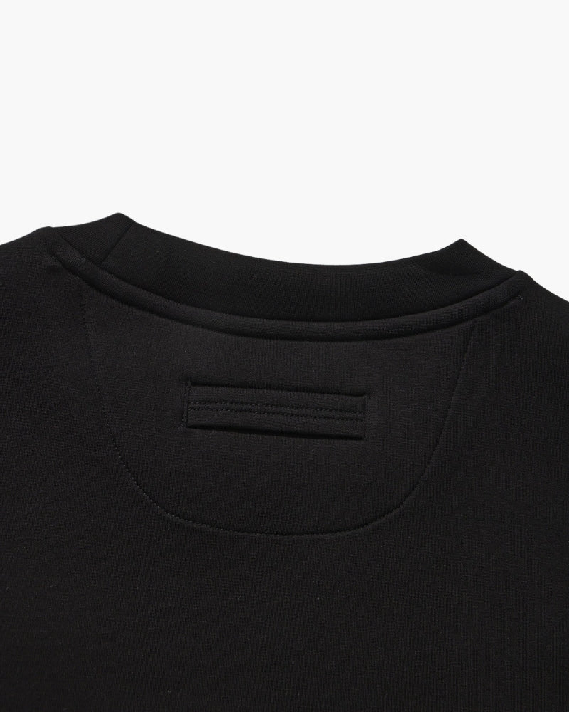 Gros plan sur l'empiècement de nuque et la patte d'un sweat col rond noir