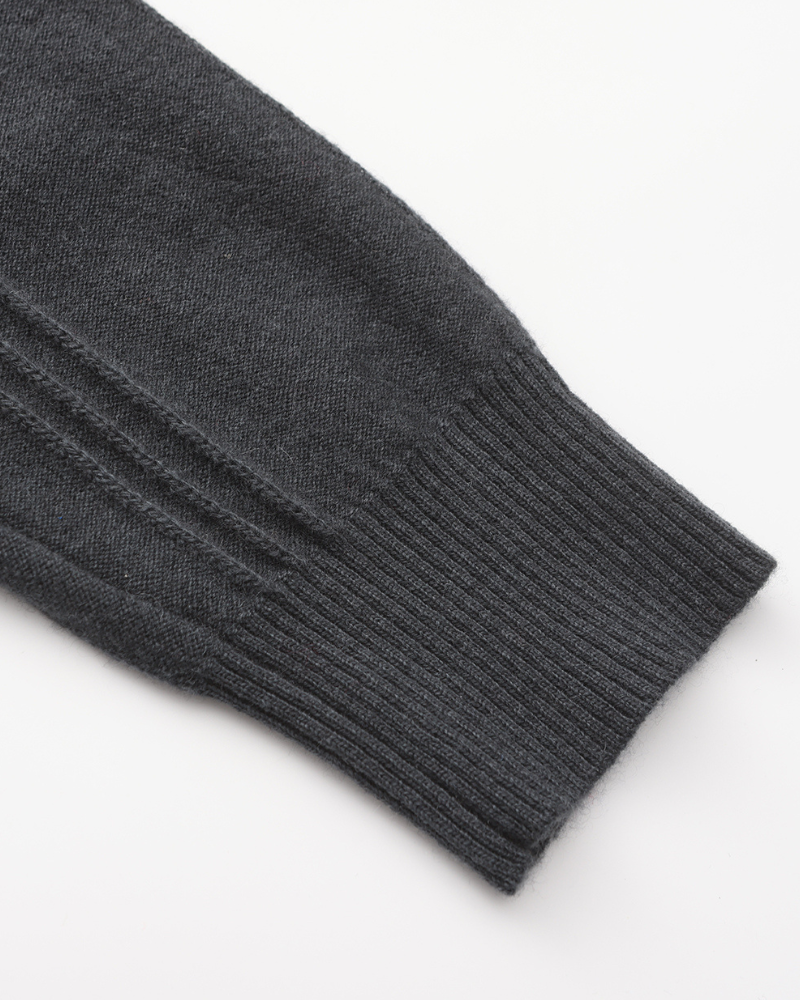 Close-up of a charcoal cashmere sleeve with ribbed cuff and vertical rib panel, flat on white