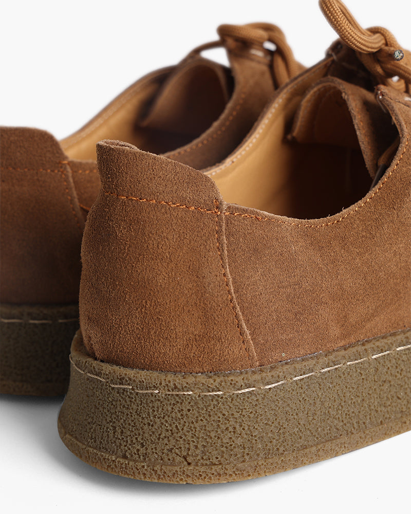 Close-up of tan suede shoe heel and gum crepe sole with contrast stitching