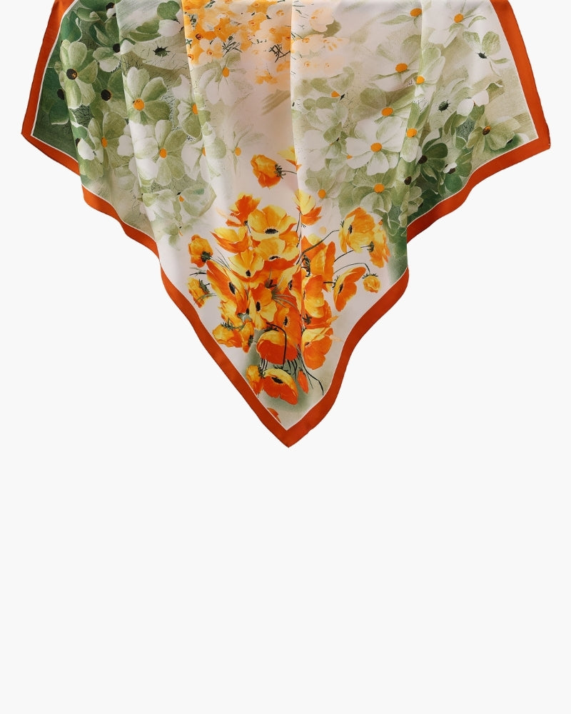 Flat-lay corner of white scarf with orange and green floral print and rust border