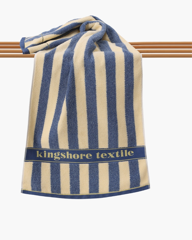 Blue and cream striped terry hand towel draped over wooden rails