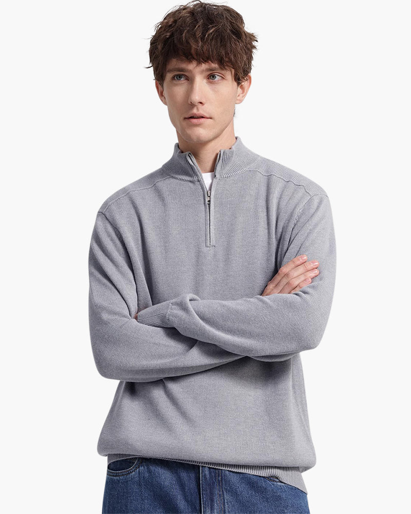 Man wearing grey quarter-zip jumper with arms crossed and blue jeans, front view