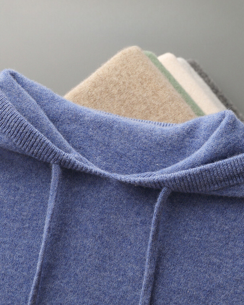 Close-up of a blue cashmere hood with ribbed edge and drawstring, with other colours folded behind