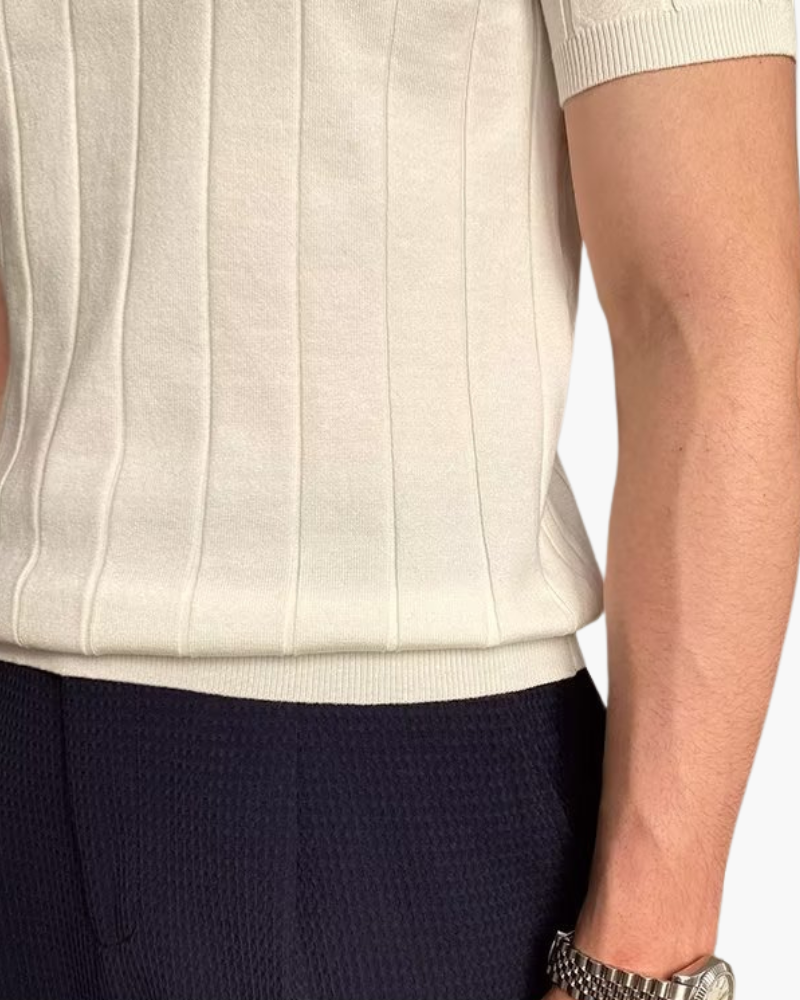 Close-up of a cream ribbed polo hem and short sleeve with navy trousers