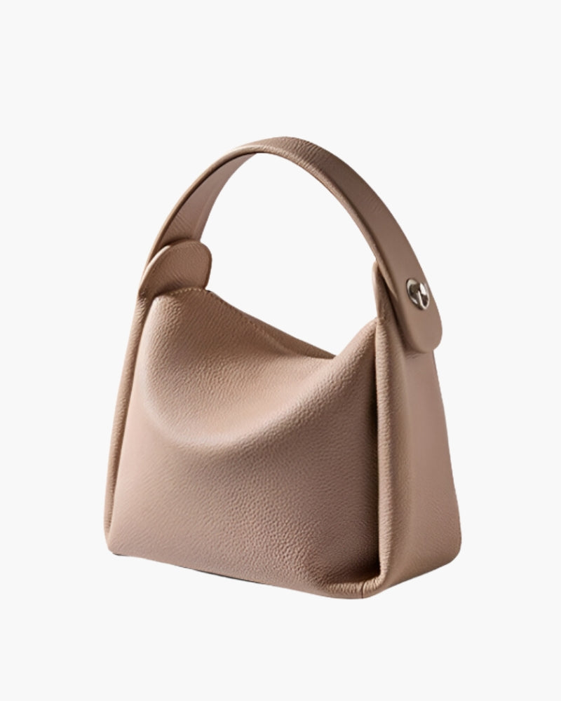 Sac à main beige en cuir grainé à anse supérieure, vue de trois quarts montrant le rivet latéral