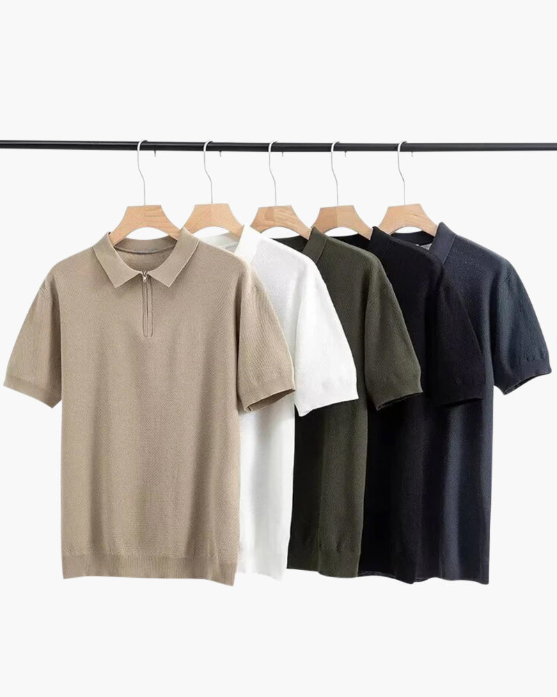 Five knit zip polos in taupe, white, green, black and navy hanging on a rail