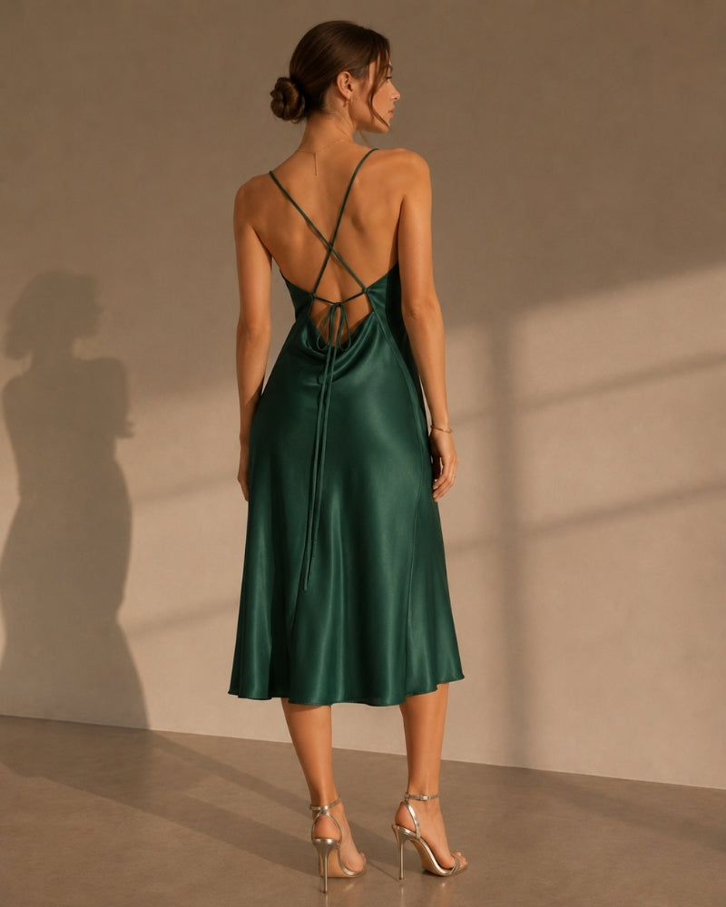 Back view of emerald satin slip dress with crossed straps and tie, worn with heels