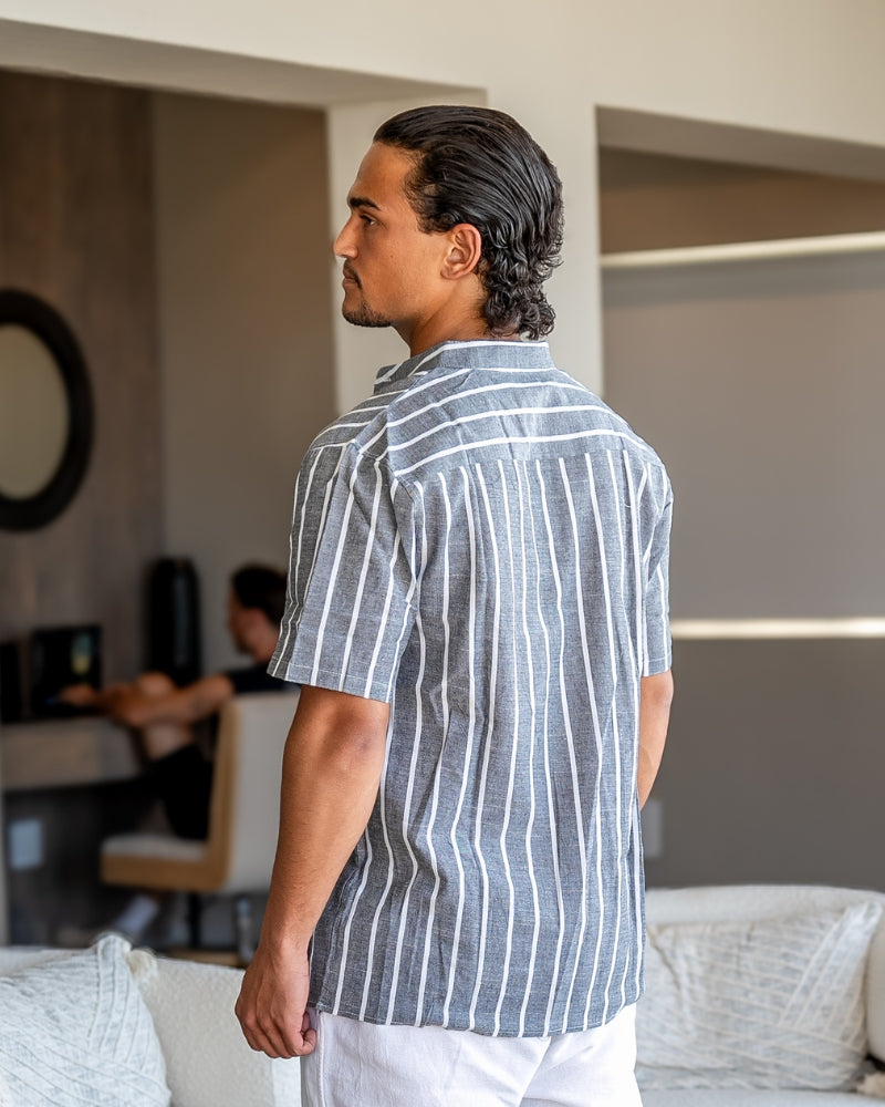 Vista trasera lateral de una camisa de rayas gris de cuello mao en modelo con pantalón blanco