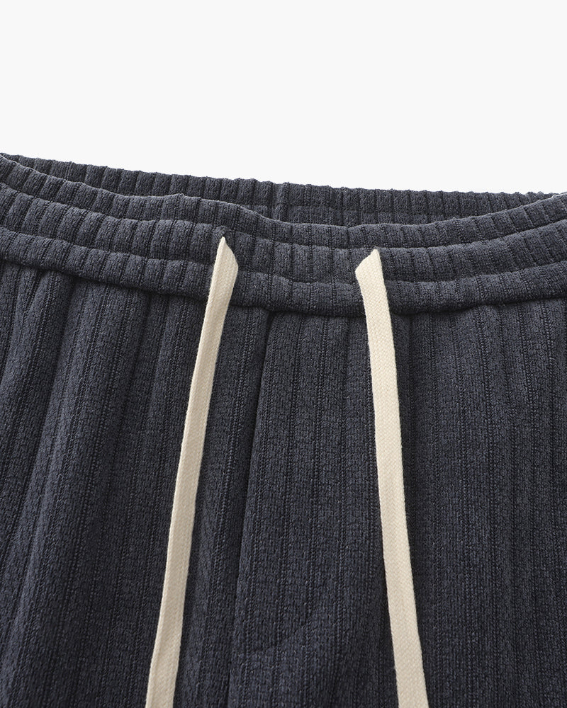 Close-up of charcoal-grey ribbed velvet trousers elastic waistband and cream drawstring cord