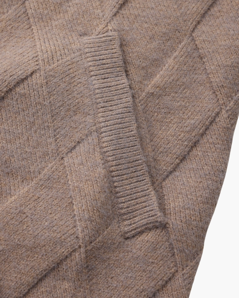 Primer plano de la abertura de bolsillo de canalé de una chaqueta de punto topo con rombos