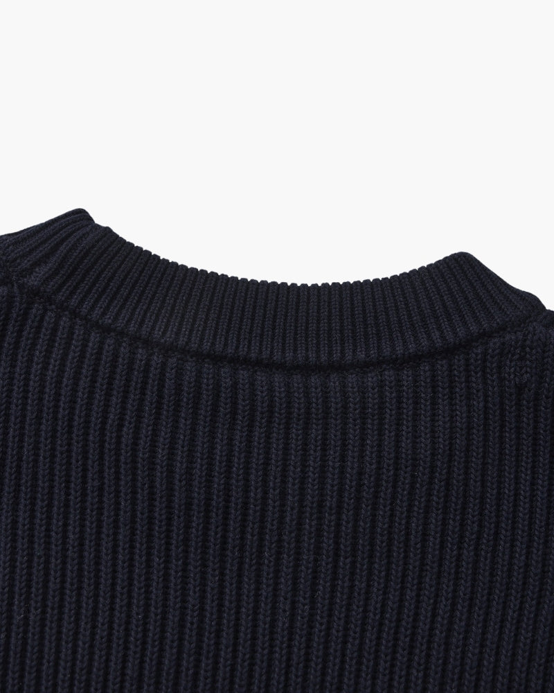 Close-up of navy rib-knit jumper crew neckline seen from behind, flat-lay on white