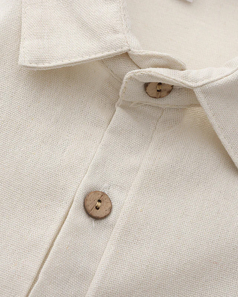 Close-up of a cream linen polo collar and two wooden coconut-shell buttons