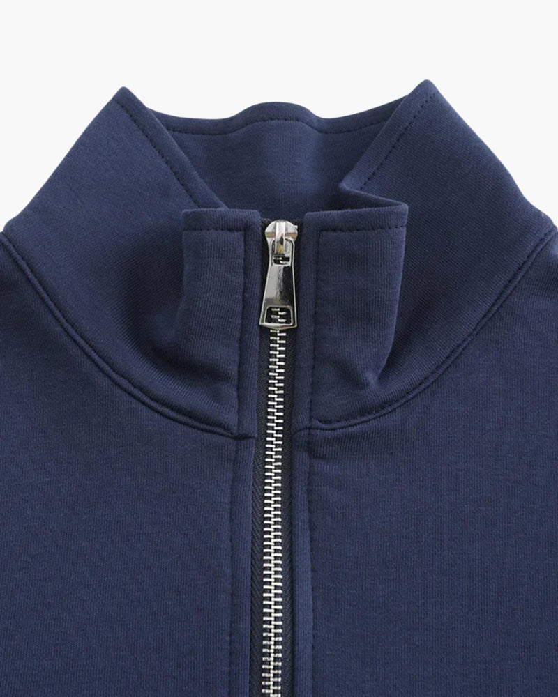Close-up of navy stand collar and silver metal half-zip puller