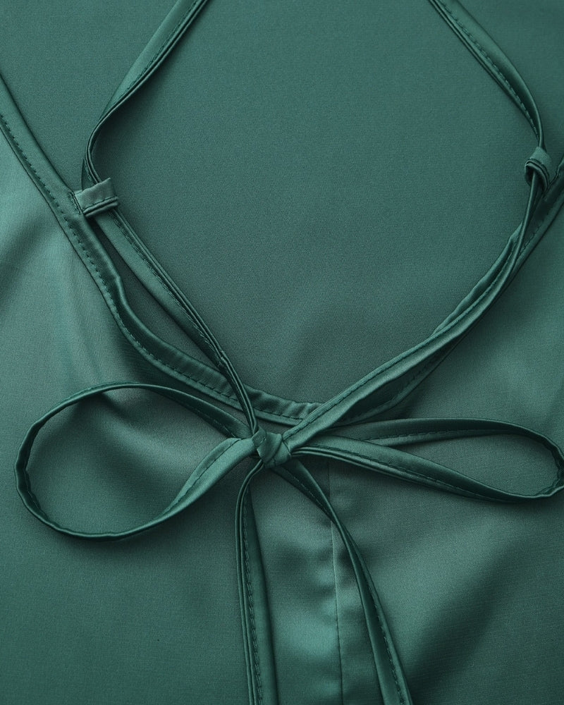 Gros plan sur les bretelles croisées nouées en nœud au dos d'une robe nuisette en satin émeraude