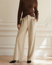Beige wide-leg trousers with a pleated front, worn with a brown ribbed jumper, front view