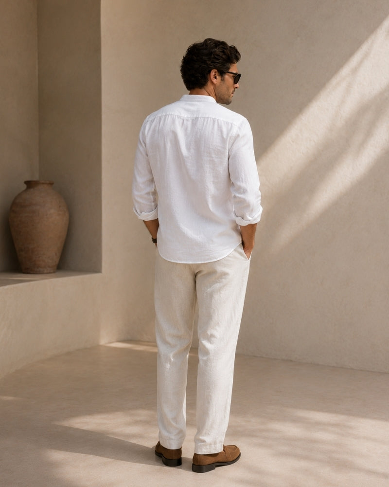 Back view of man in white mandarin collar shirt and white trousers, hands in pockets