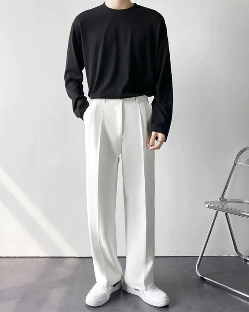 Man wearing white pleated wide-leg trousers with black top and white sneakers