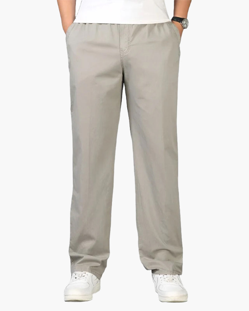 Man in light stone-grey straight cotton-linen trousers with elastic waist, white tee and trainers