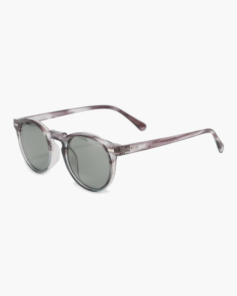Gafas de sol redondas con montura gris translúcida y lentes tintadas en verde, vista lateral en ángulo