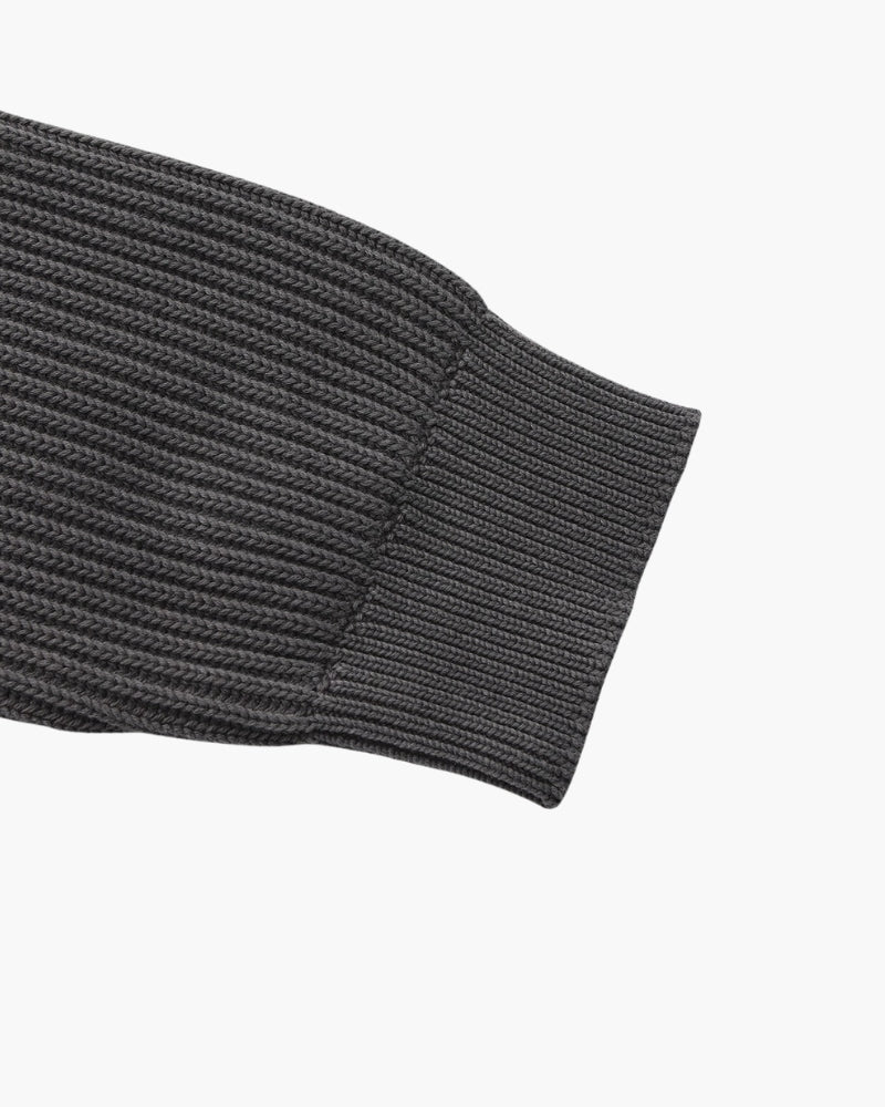 Close-up of charcoal-grey rib-knit jumper sleeve end with ribbed cuff, flat-lay on white