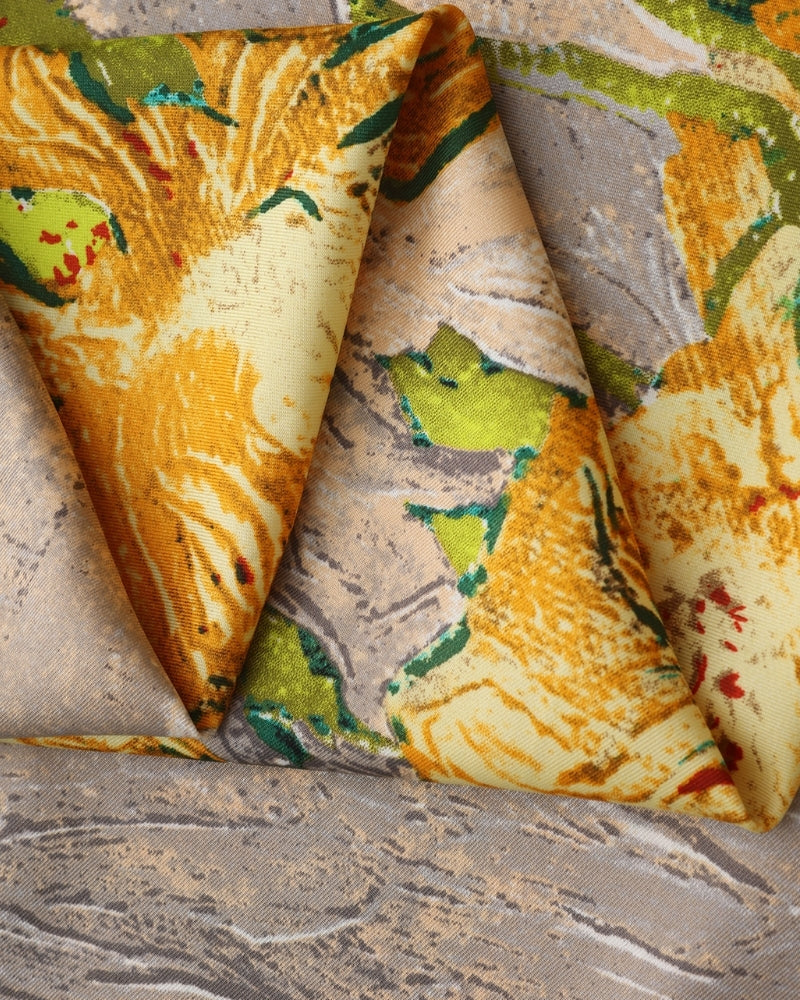Close-up of folded scarf showing yellow flowers and green leaves on grey