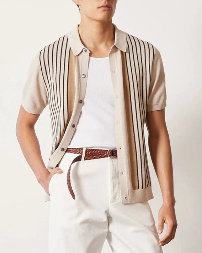 Cream striped knit polo worn open over a white tank top with white trousers and brown belt